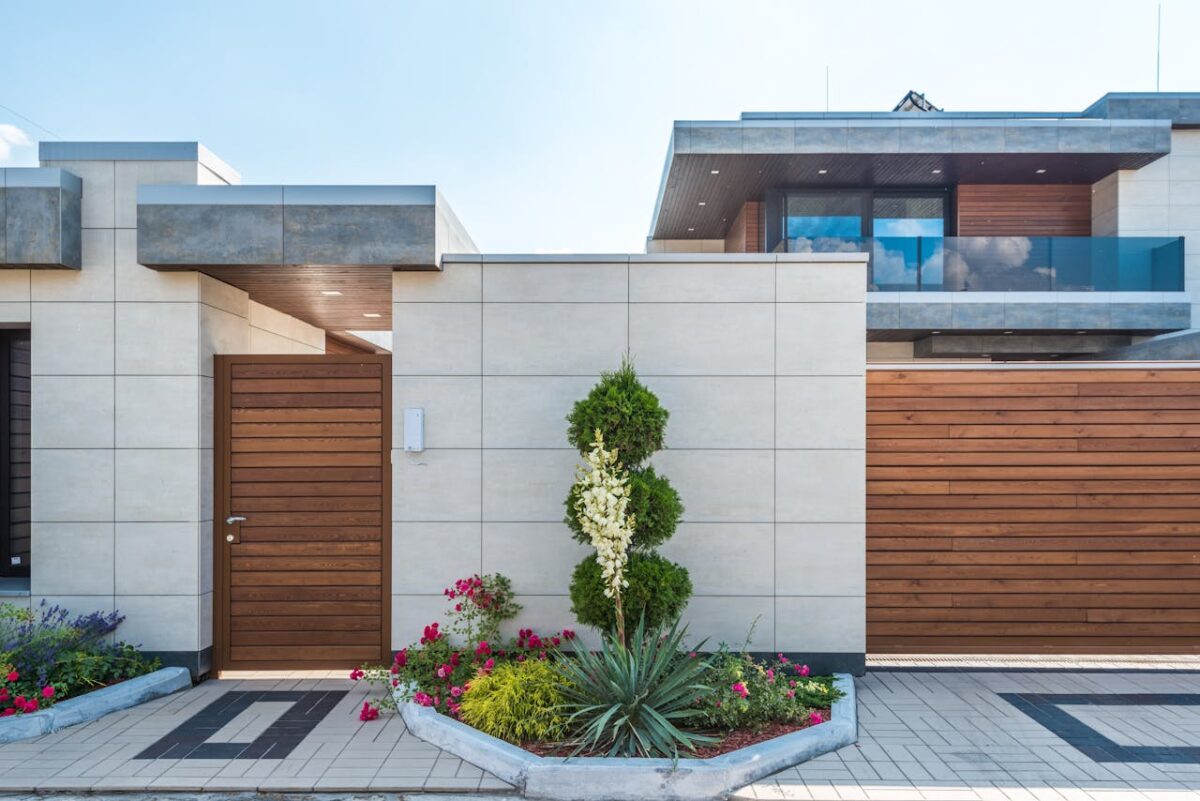get-in-touch Contemporary house exterior featuring a stylish wooden facade, entrance gate, and vibrant garden.